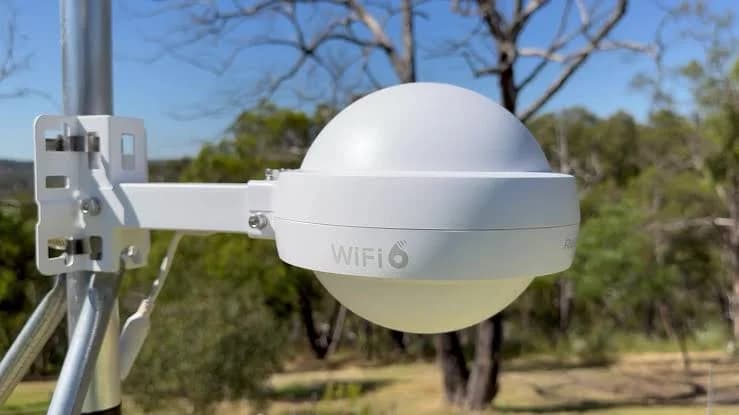 Close-up of an outdoor-rated Wi-Fi access point securely mounted above a yard