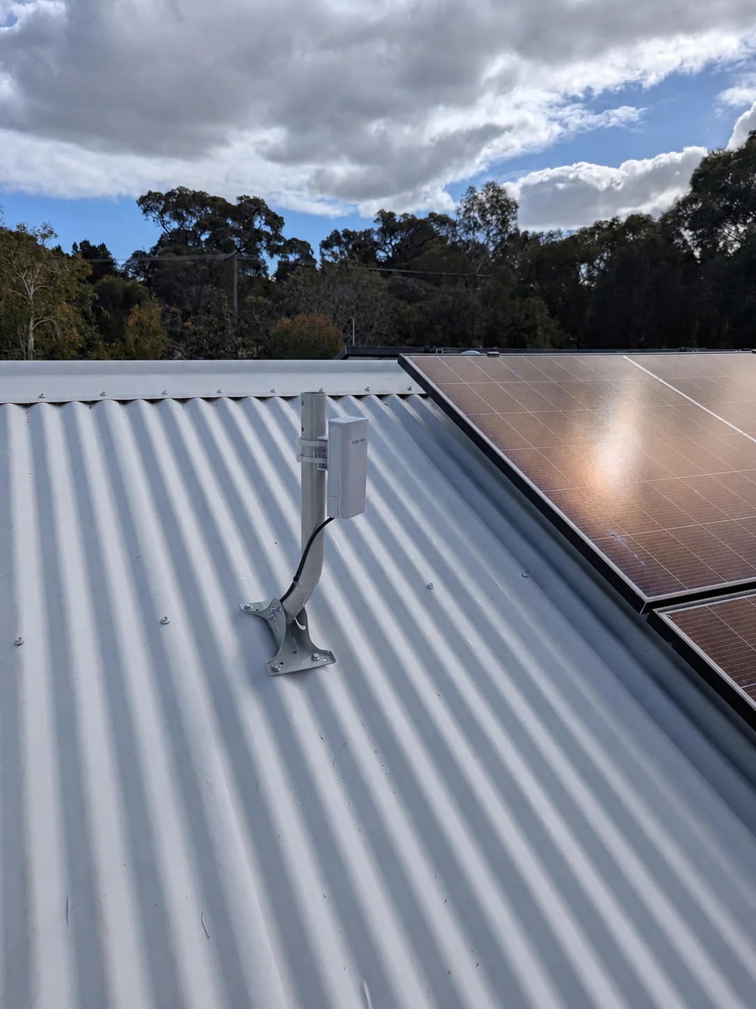 Outdoor wireless bridge securely mounted on a metal roof to connect another building