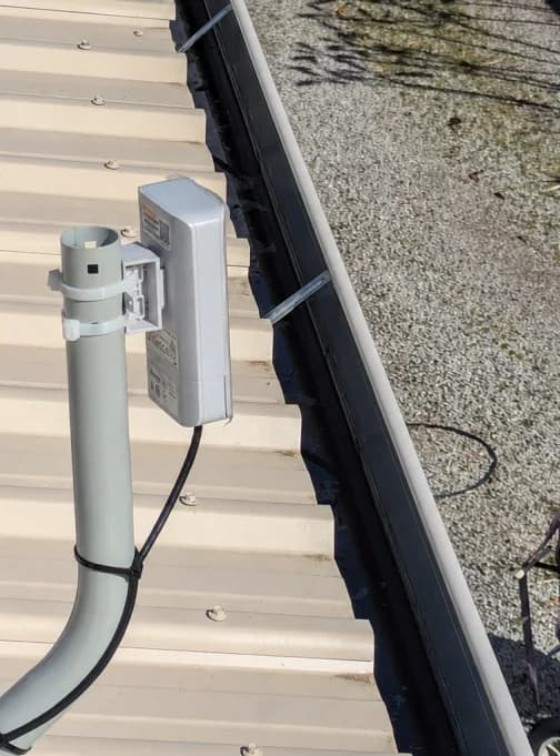 Close-up of a professionally mounted outdoor wireless bridge with protected cabling
